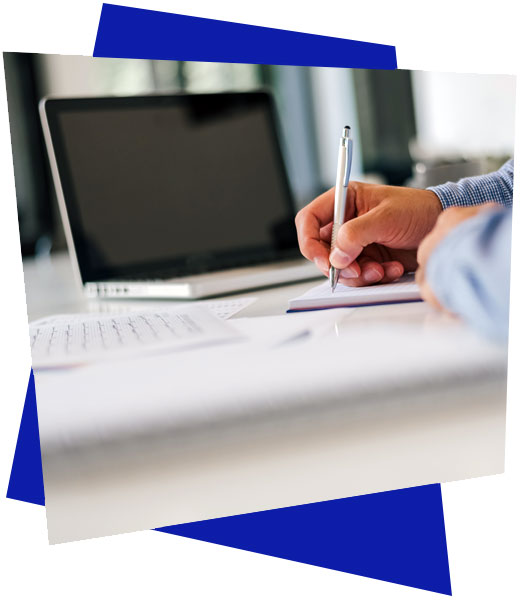 ordinateur et main qui écrit sur un bureau
